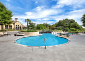 Thumbnail 15 of 35 - a pool with a stone wall and patio furniture with a house in the background