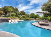 Thumbnail 19 of 35 - a swimming pool with chaise lounge chairs and an umbrella