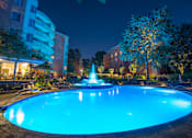 Thumbnail 38 of 45 - a swimming pool with a fountain in front of a building at night