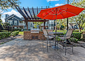 Thumbnail 35 of 52 - a patio with an umbrella and tables with chairs and a grill