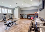 Thumbnail 11 of 13 - A home gym with a bench, weights, and exercise equipment.