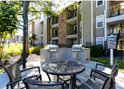 Thumbnail 12 of 13 - A patio with a table and chairs is surrounded by apartment buildings.