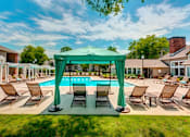 Thumbnail 3 of 13 - A pool area with a green canopy and lounge chairs.