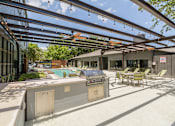Thumbnail 30 of 33 - a patio with a grill and a pool in the background
