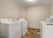 Thumbnail 23 of 36 - an empty laundry room with four white washers and dryers and two sets of