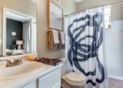 Thumbnail 28 of 52 - A bathroom with a white sink and a shower curtain with black lines.