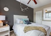 Thumbnail 27 of 52 - A bedroom with a white bed and a white nightstand.