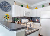 Thumbnail 24 of 52 - A kitchen with white cabinets and a marble countertop.