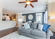 Thumbnail 22 of 52 - A grey couch with blue pillows is in the center of a room with a ceiling fan.