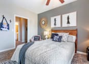 Thumbnail 26 of 52 - A bedroom with a bed, a ceiling fan, and a wall hanging.