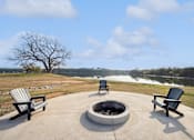 Thumbnail 34 of 36 - two adirondack chairs sit around a fire pit with a lake in the background
