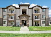 Thumbnail 33 of 33 - a tan and brown apartment building with a sidewalk and grass