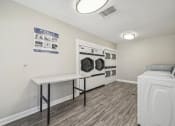 Thumbnail 25 of 40 - a washer and dryer in a laundry room with white walls and wood floors