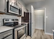 Thumbnail 5 of 35 - A kitchen with a white tile backsplash and stainless steel appliances.