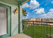 Thumbnail 11 of 35 - A balcony with a green door and a black railing.