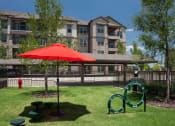 Thumbnail 17 of 28 - a park with a red umbrella in front of an apartment building