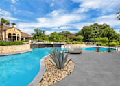 Thumbnail 18 of 35 - Poolside view with in-water loungers, umbrella seating, and lush green landscaping.