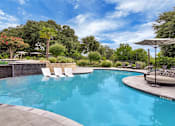 Thumbnail 19 of 35 - Swimming pool with in-water chaise loungers, shaded daybed, and lounge chairs.