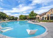 Thumbnail 21 of 35 - Wide view of the freeform pool with in-water loungers and surrounding sun deck.