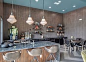 Thumbnail 29 of 35 - Clubhouse kitchen and bar with large island seating, pendant lights, and open shelving.