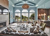 Thumbnail 27 of 35 - Resident lounge with arched windows, chandelier lighting, and seating near a bar.