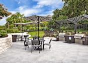 Thumbnail 24 of 35 - Community grilling pavilion with covered stations, patio tables, and umbrella seating.