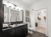 Thumbnail 14 of 35 - Bathroom with single vanity, large mirror, and adjacent walk-in closet entry.