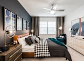 Thumbnail 8 of 35 - Primary bedroom with ceiling fan, upholstered bed, accent wall, and large window.