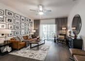 Thumbnail 1 of 35 - Parkview Terraces living room with leather sofa, gallery wall, and sliding patio doors.