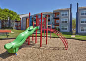 Thumbnail 20 of 21 - a playground with a slide in front of an apartment building