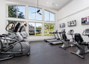 Thumbnail 13 of 25 - A gym with a row of stationary bikes and a fan.