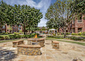 Thumbnail 15 of 25 - A stone fire pit sits in the middle of a courtyard.