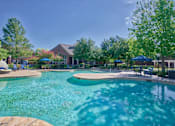 Thumbnail 19 of 25 - A large swimming pool surrounded by trees and umbrellas.