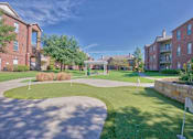 Thumbnail 23 of 25 - A sunny day at a residential complex with a green lawn and brick buildings.
