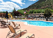 Thumbnail 1 of 18 - a pool with lounge chairs and a slide at the foot of a mountain