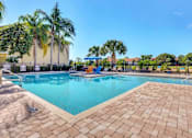 Thumbnail 23 of 42 - a resort style swimming pool with chaise lounge chairs and palm trees