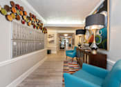 Thumbnail 31 of 45 - a hallway with blue couches and chairs and a large painting on the wall