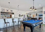 Thumbnail 18 of 36 - a pool table in a living room with a bar and a kitchen