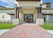 Thumbnail 18 of 38 - the entrance to a building with a brick pathway and wood doors