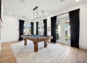 Thumbnail 26 of 38 - a game room with a pool table and windows with black curtains