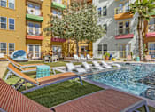 Thumbnail 31 of 35 - a pool with lounge chairs and a tree in front of a building