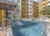 Thumbnail 33 of 35 - a swimming pool with a waterfall in front of an apartment building