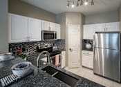 Thumbnail 16 of 50 - a kitchen with granite countertops and white cabinets