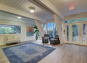 Thumbnail 9 of 23 - a living room with a blue rug and chairs and a large window