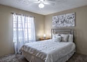 Thumbnail 6 of 30 - A bedroom with a bed, pillows, a ceiling fan, and a painting on the wall.