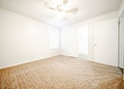 Thumbnail 19 of 47 - an empty living room with a ceiling fan and white walls