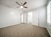 Thumbnail 24 of 47 - an empty living room with a ceiling fan and white walls