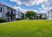 Thumbnail 10 of 27 - A grassy area in front of apartment buildings.
