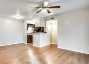 Thumbnail 5 of 15 - an empty living room with a ceiling fan and a kitchen