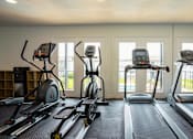 Thumbnail 9 of 27 - A row of treadmills and elliptical machines in a gym.